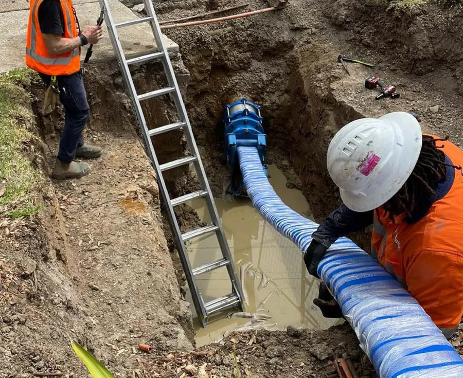 Two men working on a pipe in a construction site